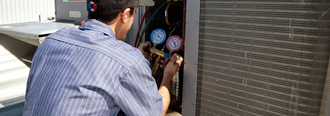HVAC technician servicing a condenser unit in Prospect Park